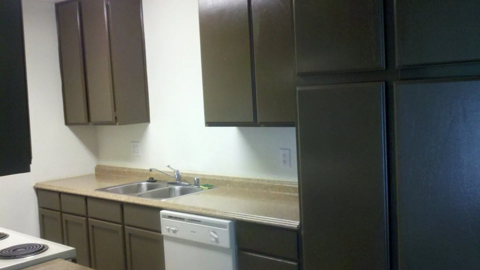 Clean kitchen with brown cabinets and white appliances.
