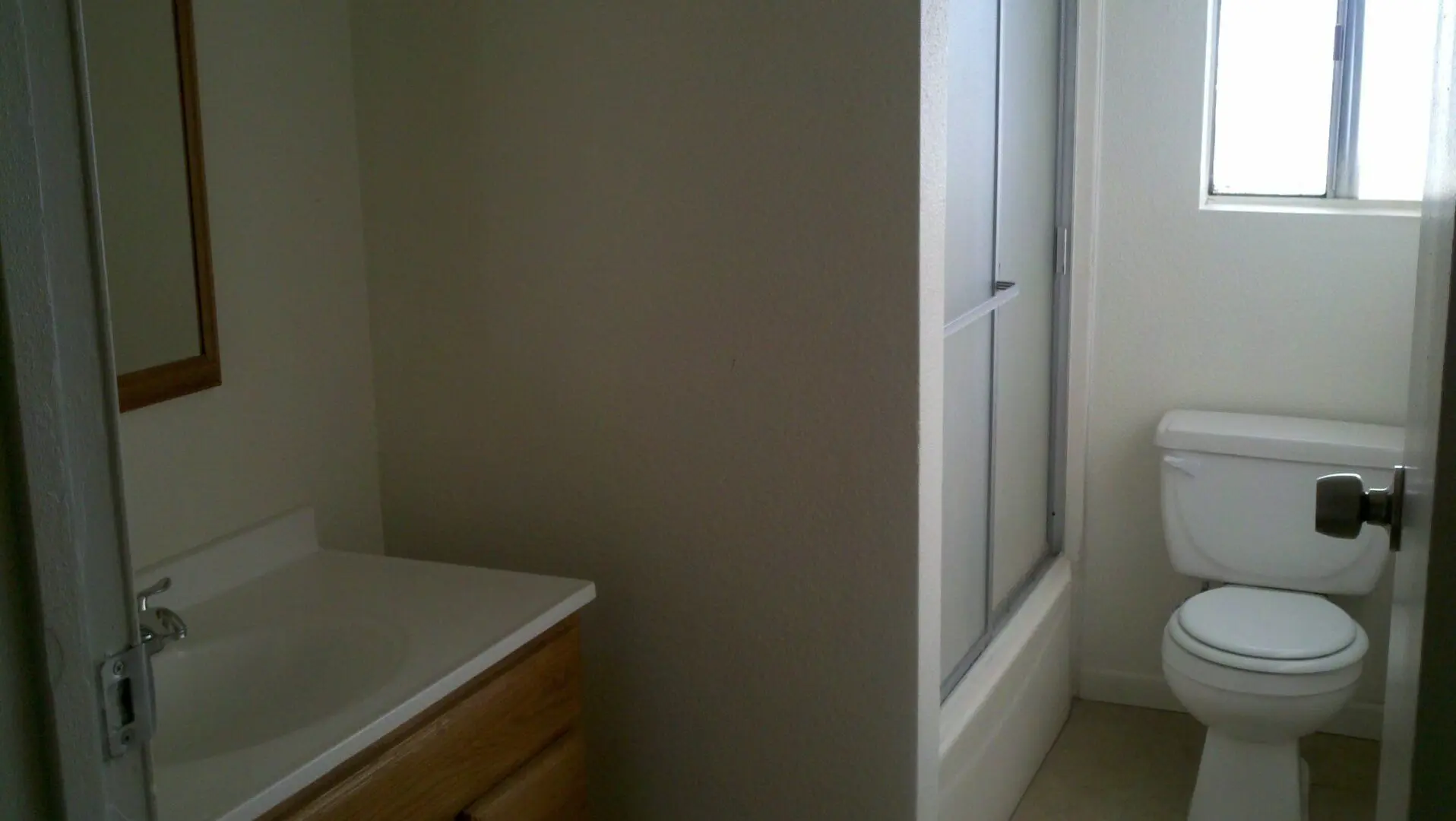 A bathroom with a wooden vanity and a shower stall.