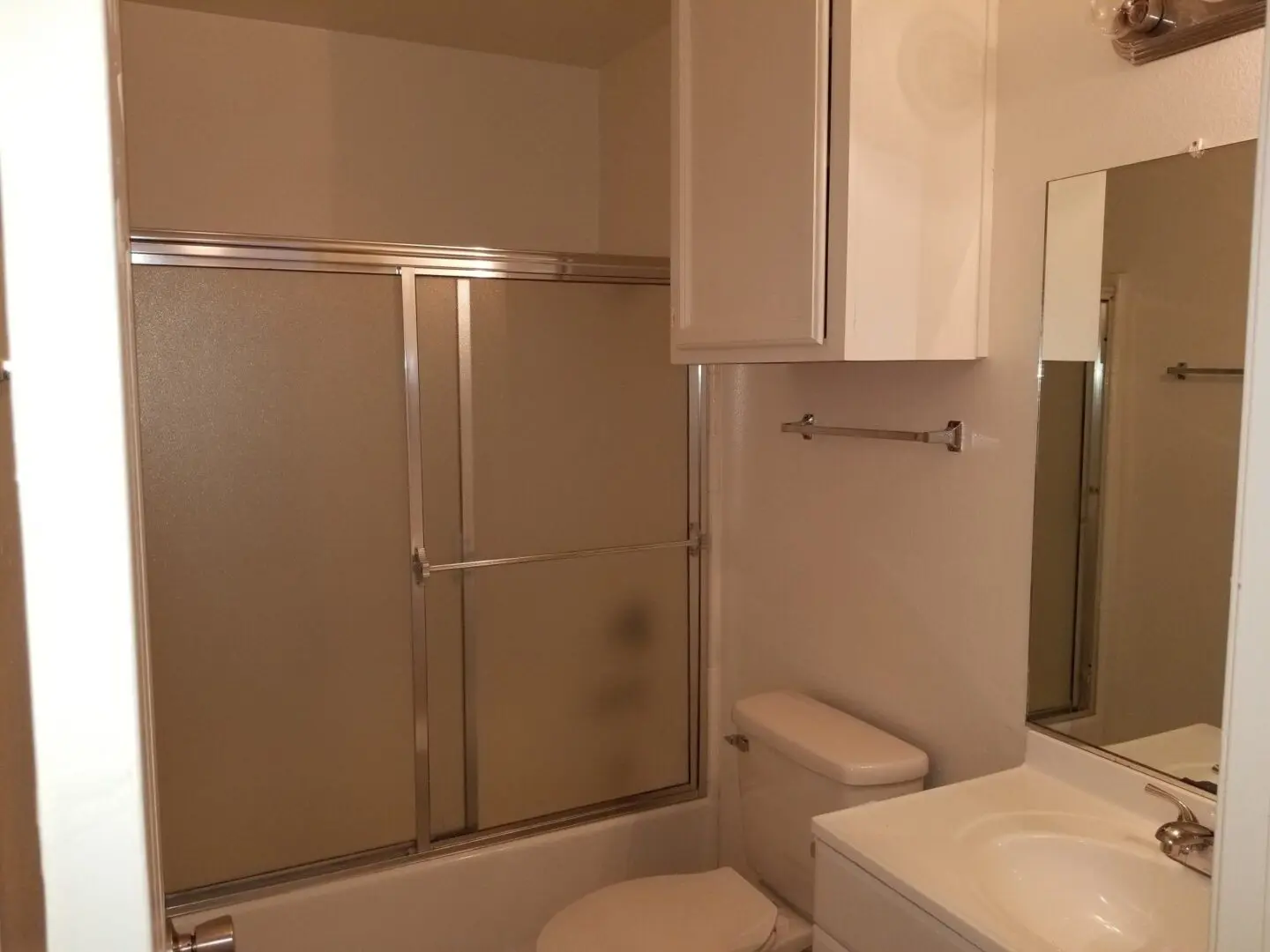 Small bathroom with glass shower doors and a white toilet.
