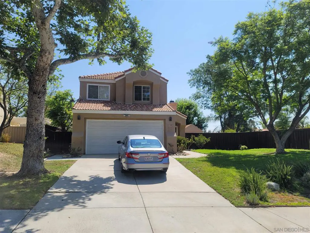 A two-story suburban house with a car parked in the driveway.