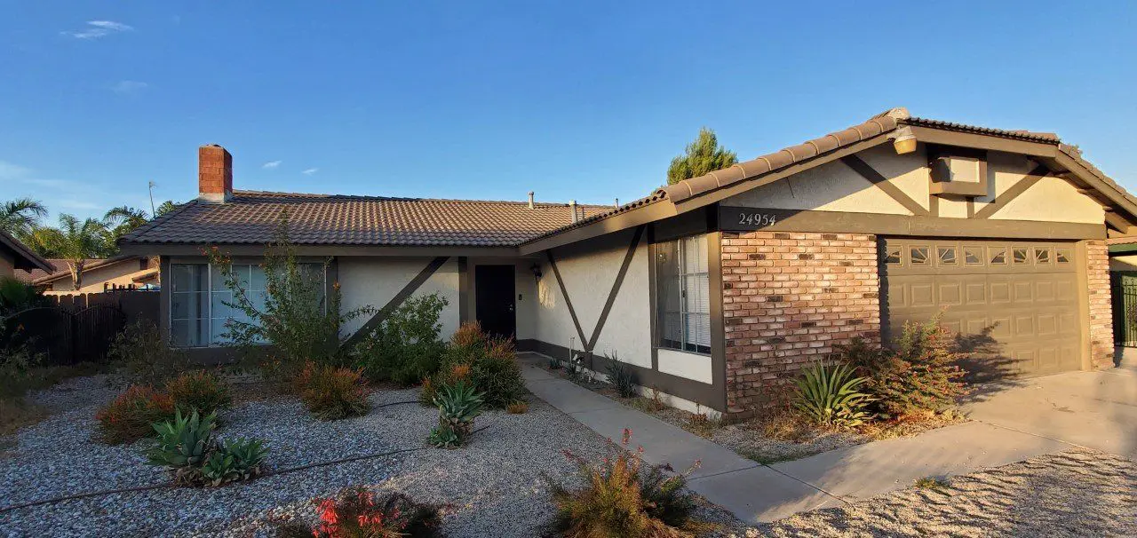 Single-story house with brick and wood exterior under clear sky.