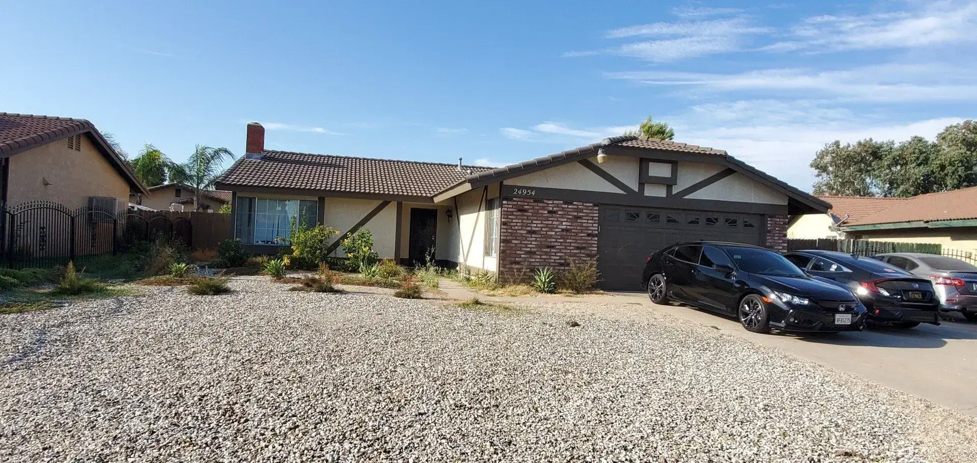 Single-story house with brick and wooden exterior and gravel driveway.