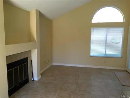 Empty living room with beige walls and fireplace.