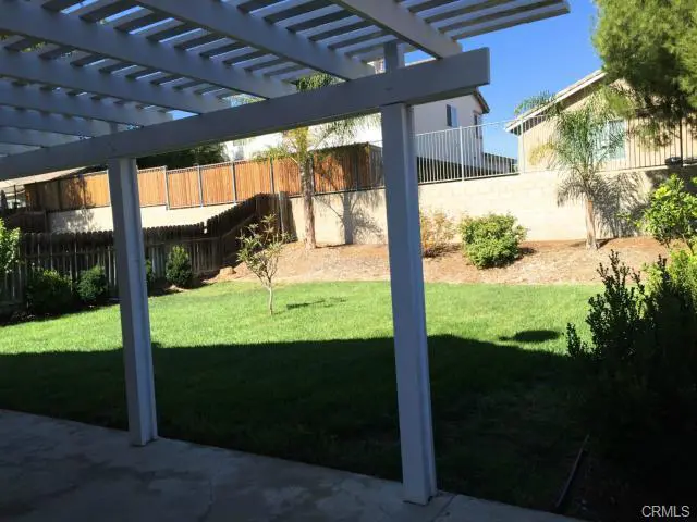 Backyard with green grass and a covered patio area.