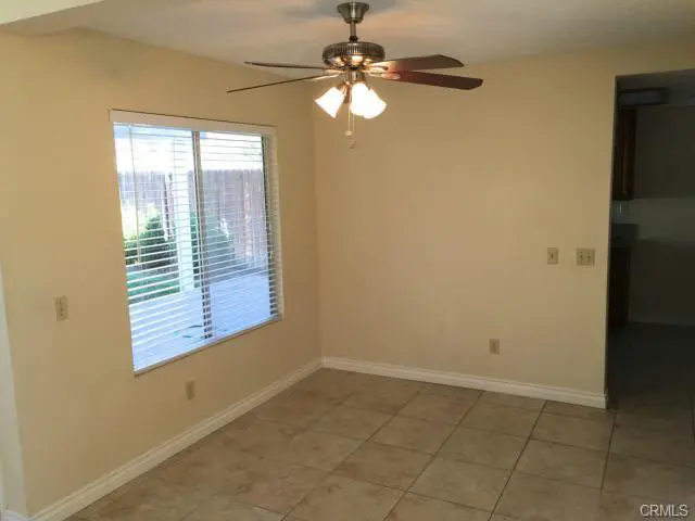Empty room with tiled floor, beige walls, ceiling fan, and window.