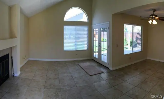 Empty room with tiled floors and large windows letting in natural light.