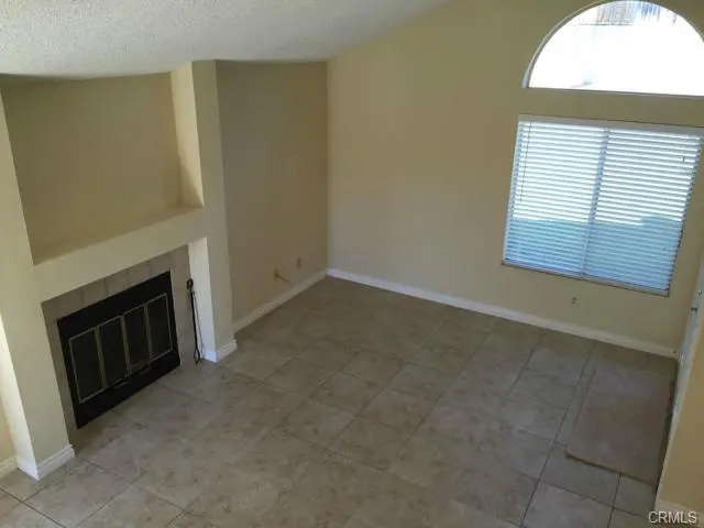 Empty living room with fireplace and tiled floor.