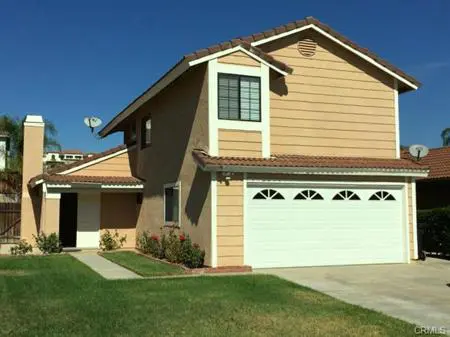 A two-story suburban house with a beige exterior and a double garage.