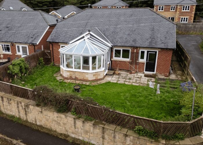 Brick house with conservatory and green lawn.