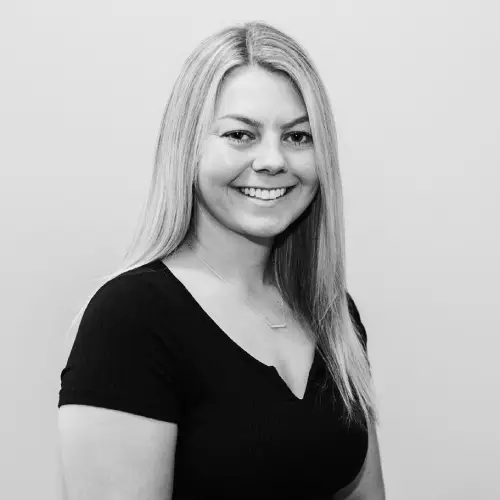 Black and white portrait of a smiling woman with long hair in a black top.