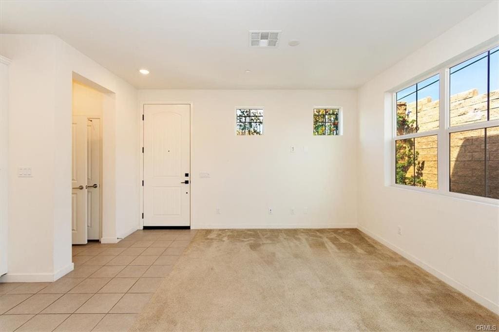 Empty room with tiled entryway and windows.