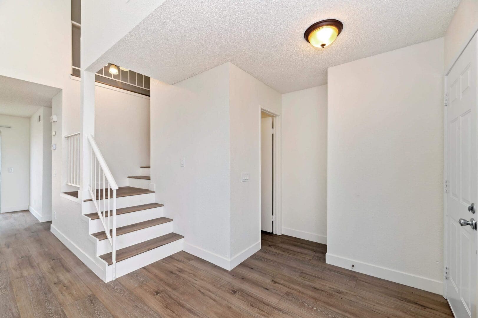 Bright hallway with wooden stairs and flooring.
