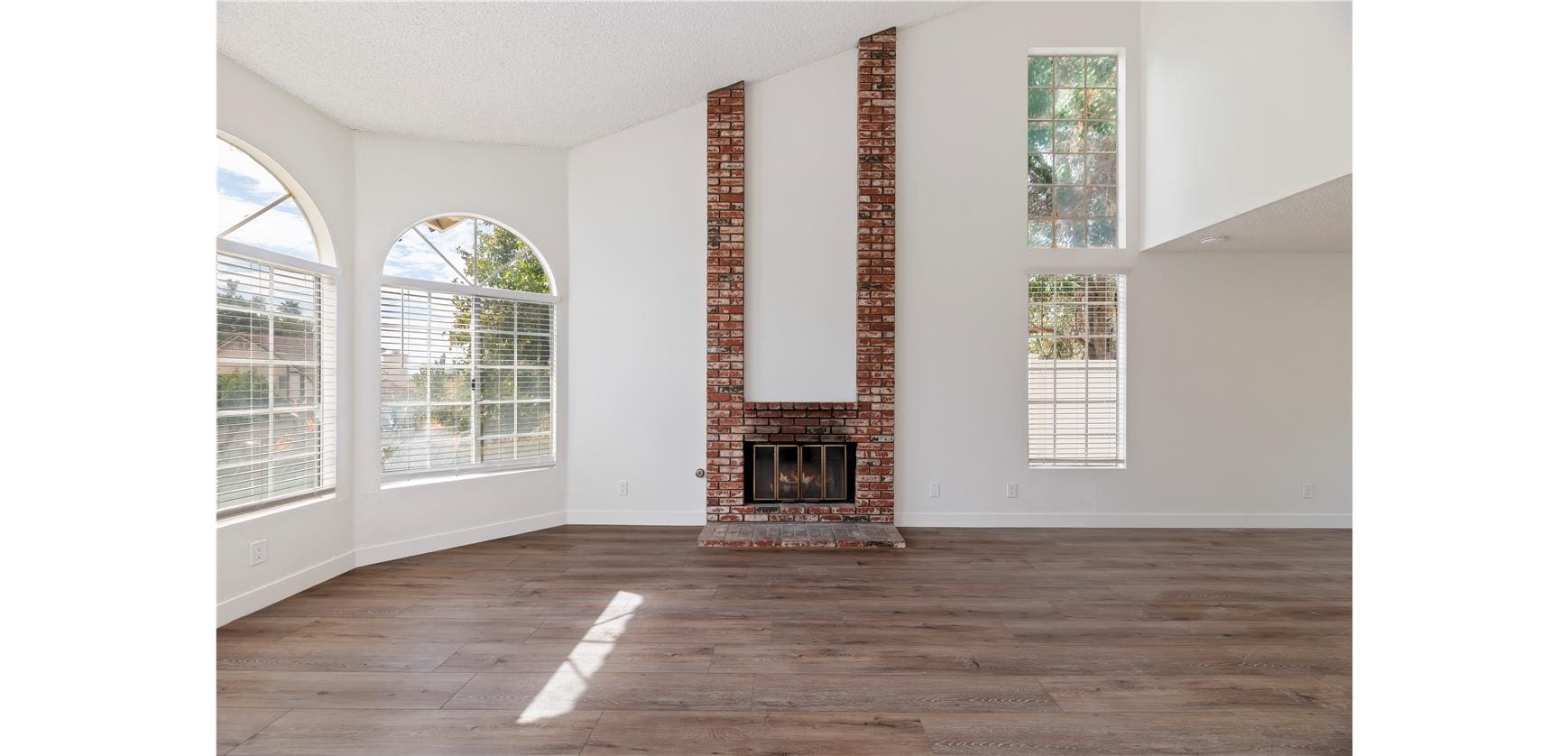 Spacious room with brick fireplace and windows.