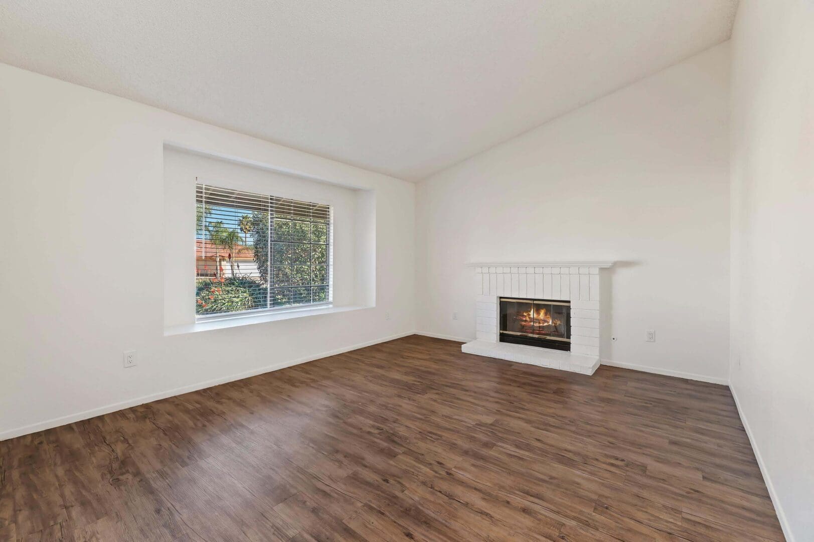 Empty room with fireplace and large window.