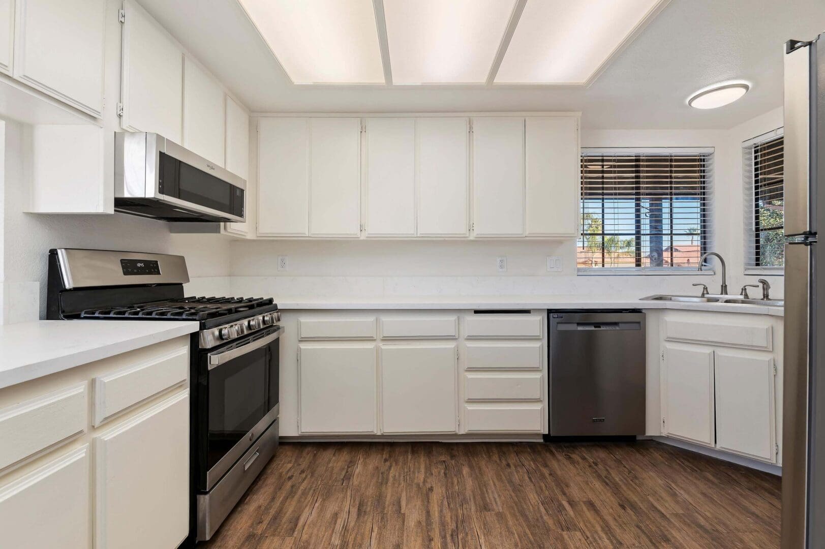 Modern kitchen with wooden floor and appliances.
